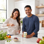 A smiling man and woman in a bright, modern kitchen. The woman is pouring water from a glass pitcher into a glass, and the man is holding a jar of Kethi Mega dietary supplement.